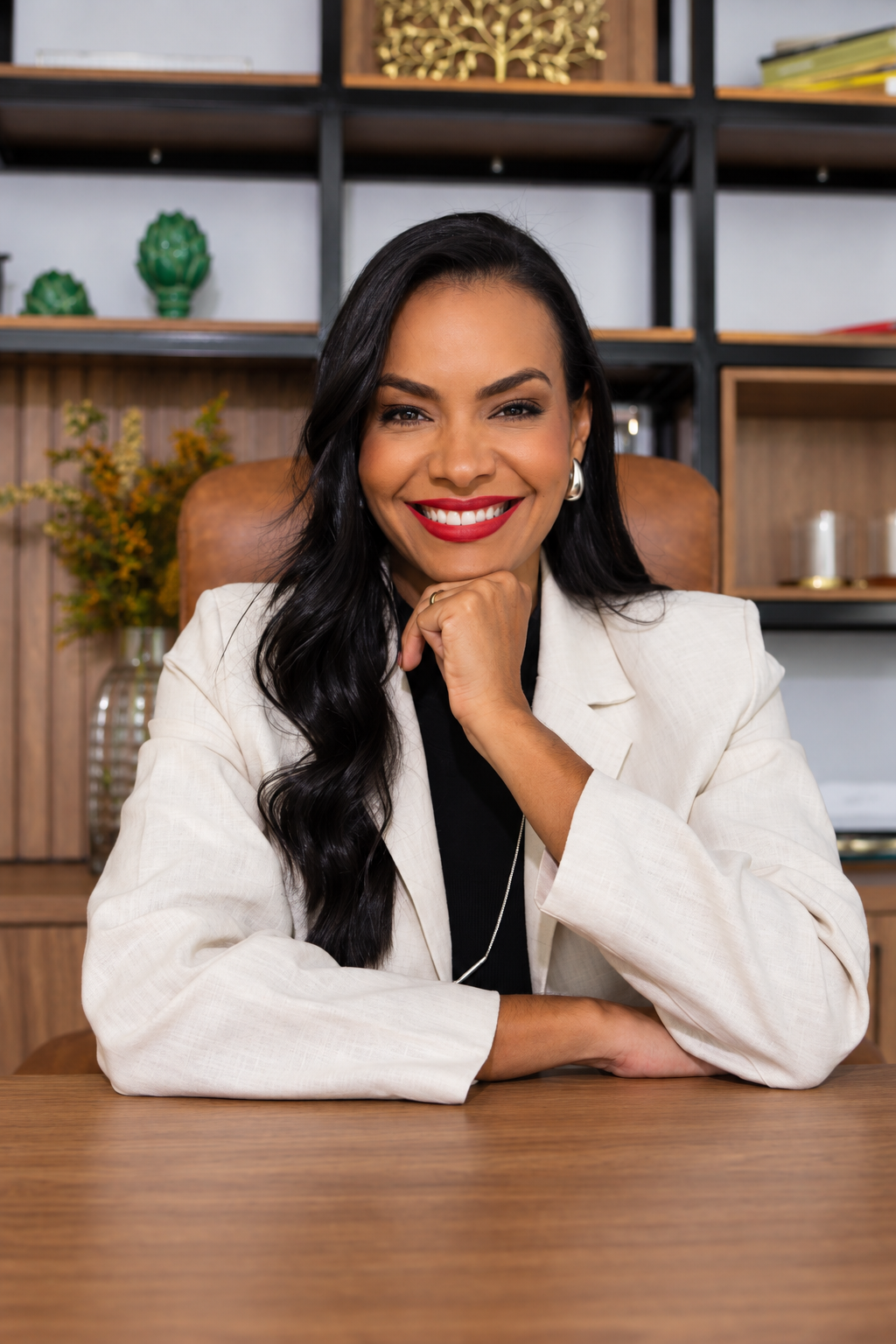 Daniela Rocha sorrindo, sentada à mesa de seu escritório